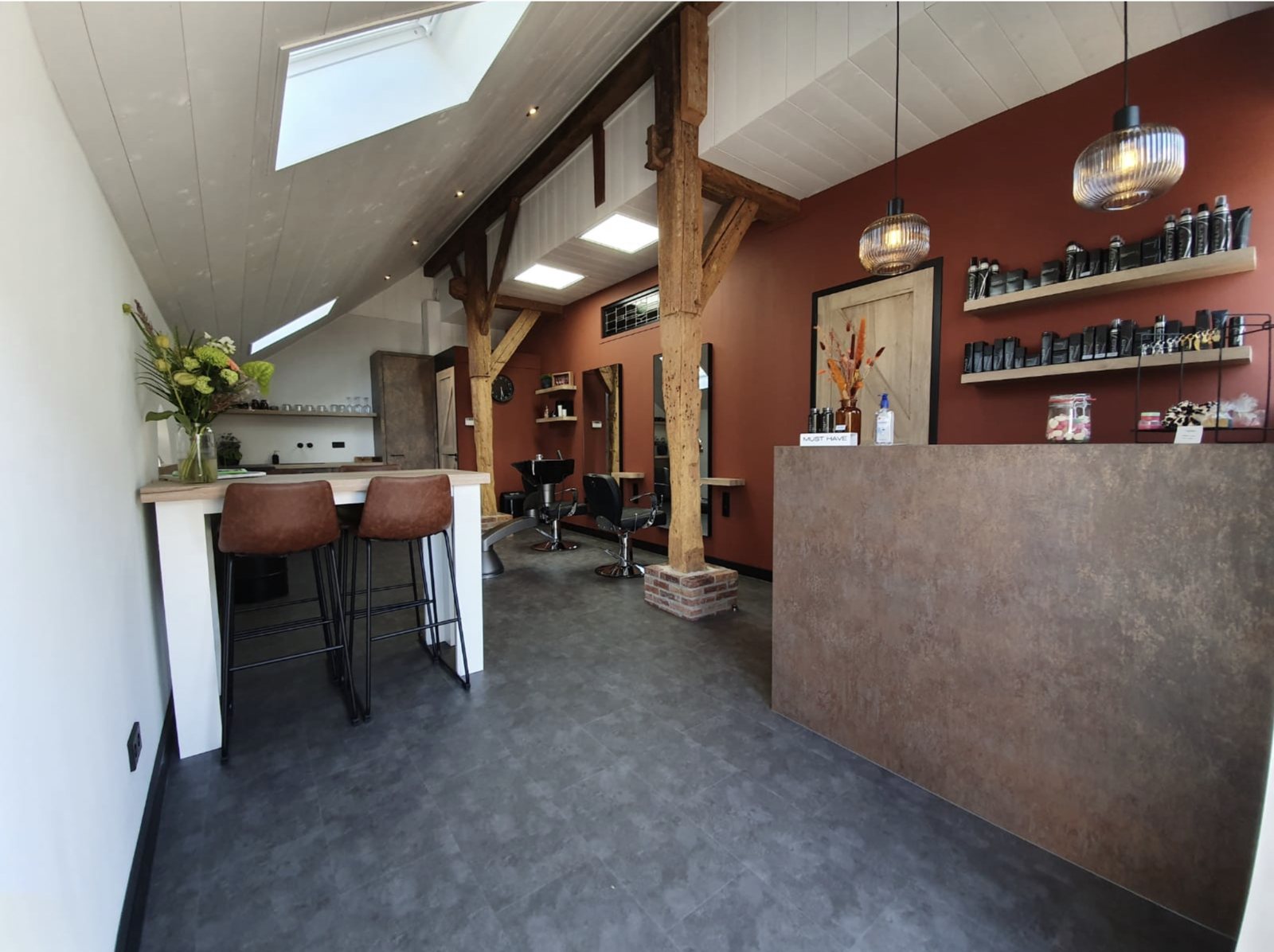 De salon: eiken balken, een dakraam, de terracotta wand, de balie en planken met haarproducten